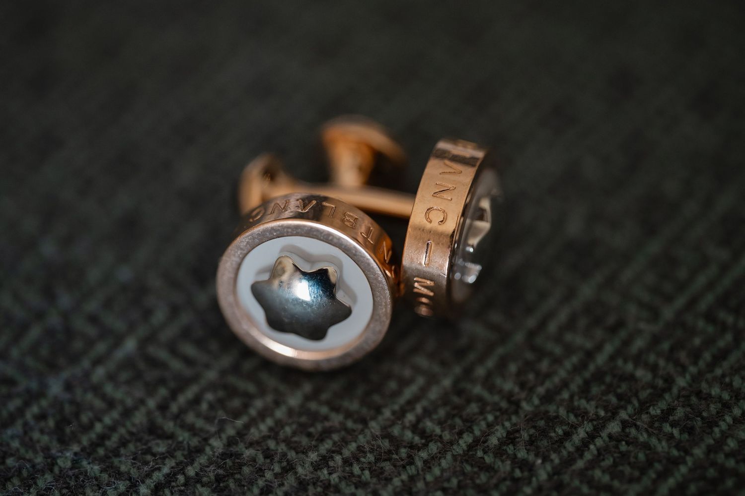 Macro shot of gold jewelry connectors and clasps on dark textured fabric background.
