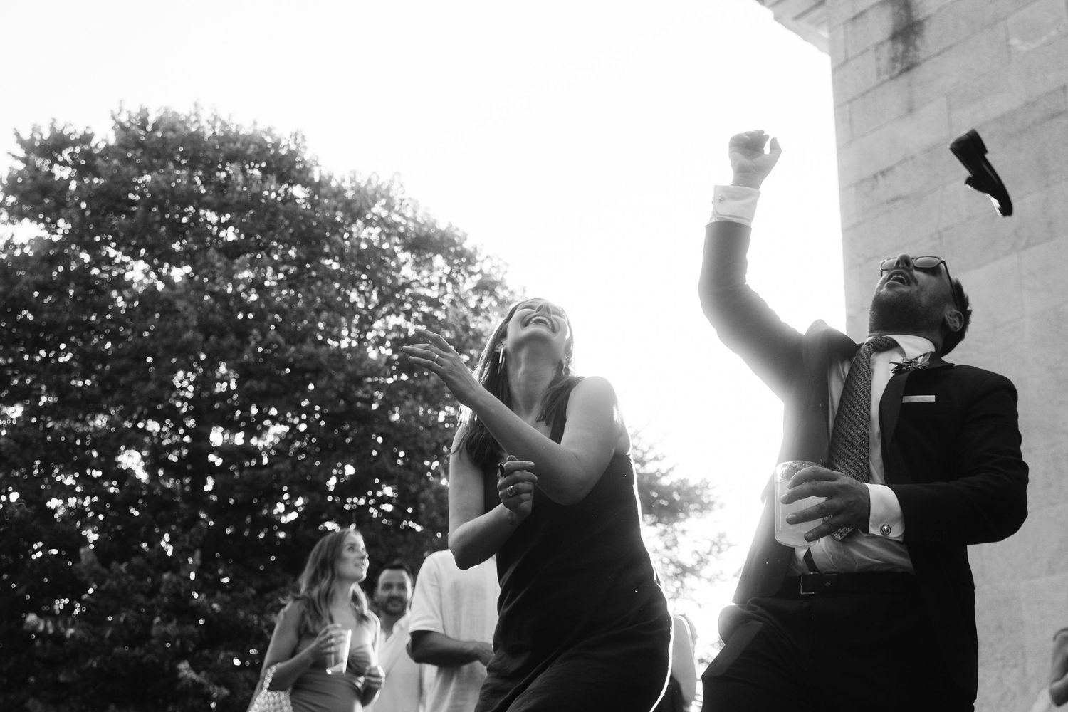 A sequence of black and white wedding photos showing joyful celebration moments outdoors.