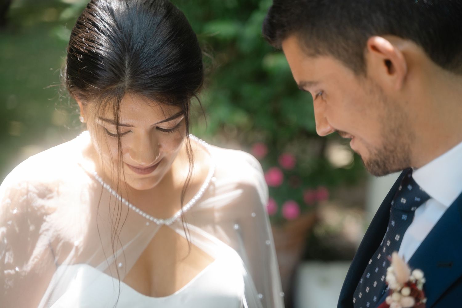 Couple shares an intimate moment while sitting on grass during a romantic outdoor wedding photoshoot.