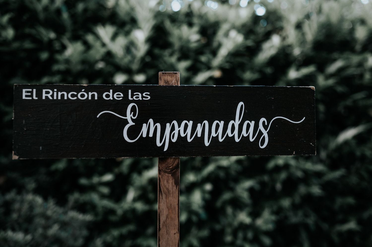 Decorative rustic wooden signs with cursive text displayed in a dark moody setting.