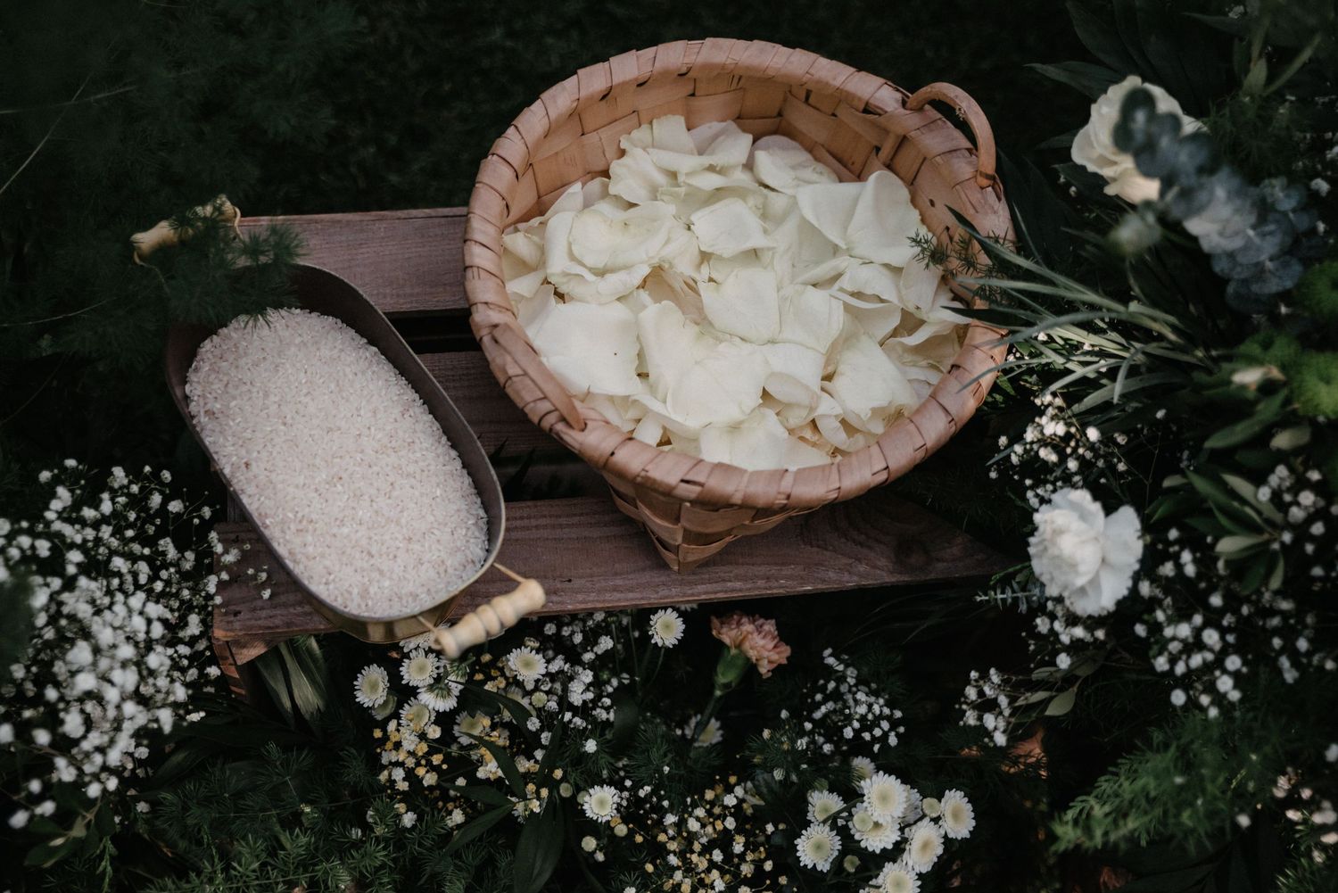 Rustic wooden table display of white flower petals and decorative elements for a wedding.