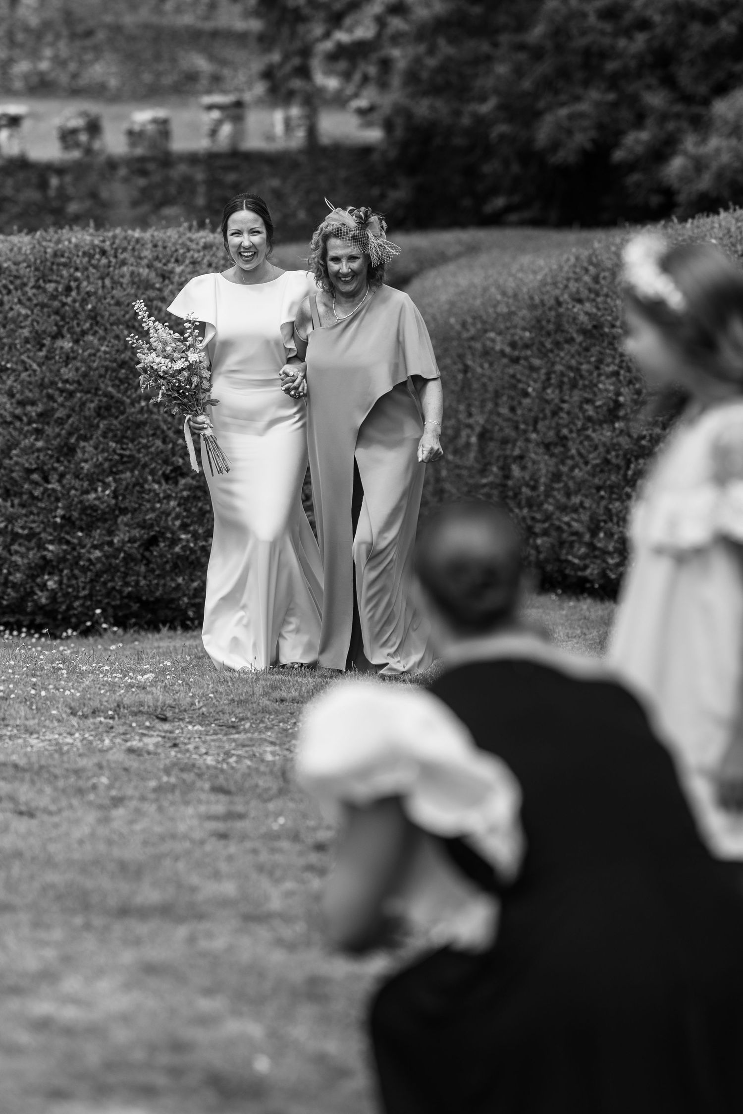 Black and white photo showing wedding guests gathered on a grassy lawn.