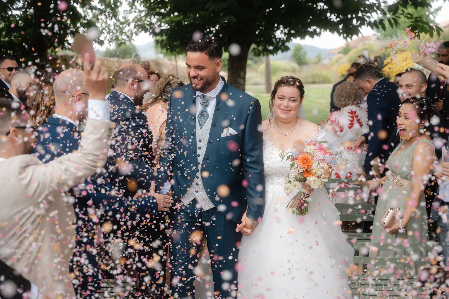 Joyful wedding party showered in confetti during outdoor celebration.