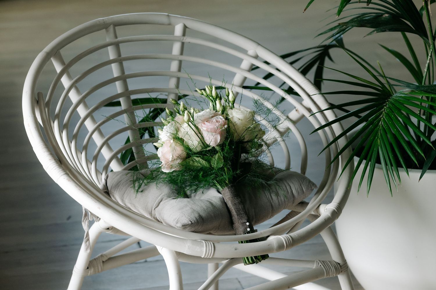 A white circular spiral staircase with wooden steps and green plants decorating the surrounding space.