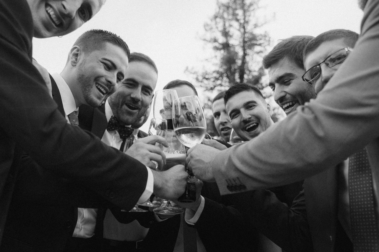 A group of friends in formal attire toast with champagne glasses at an outdoor celebration.