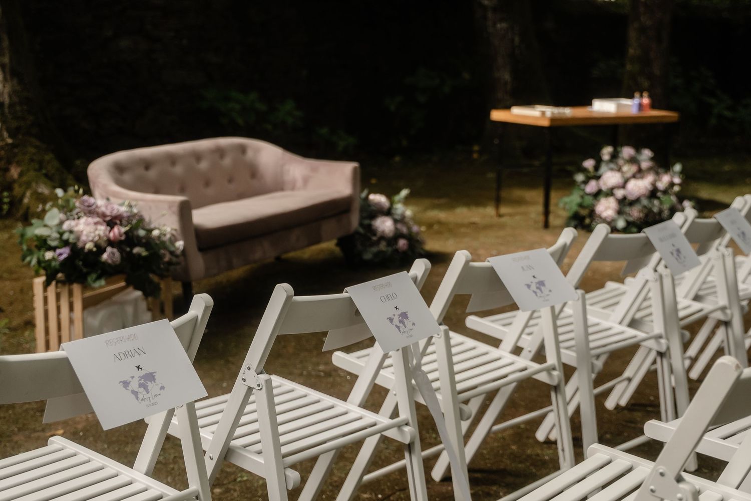 White folding chairs arranged in rows for an outdoor ceremony with natural woodland backdrop.