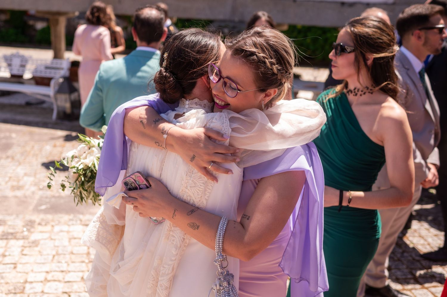 Wedding guests share emotional embrace during outdoor celebration.