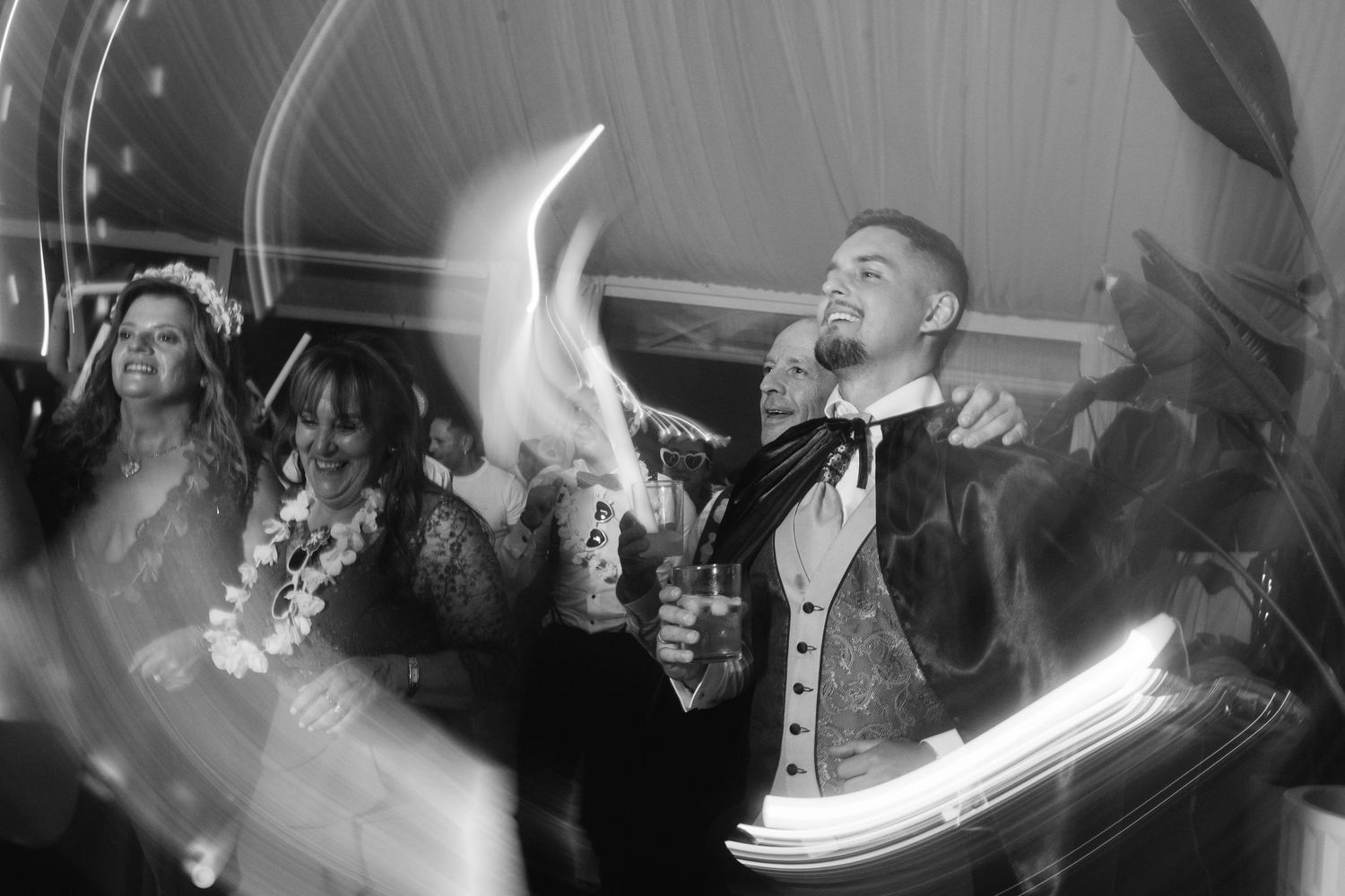 Energetic crowd at a concert venue with people jumping and dancing under dramatic lighting effects.