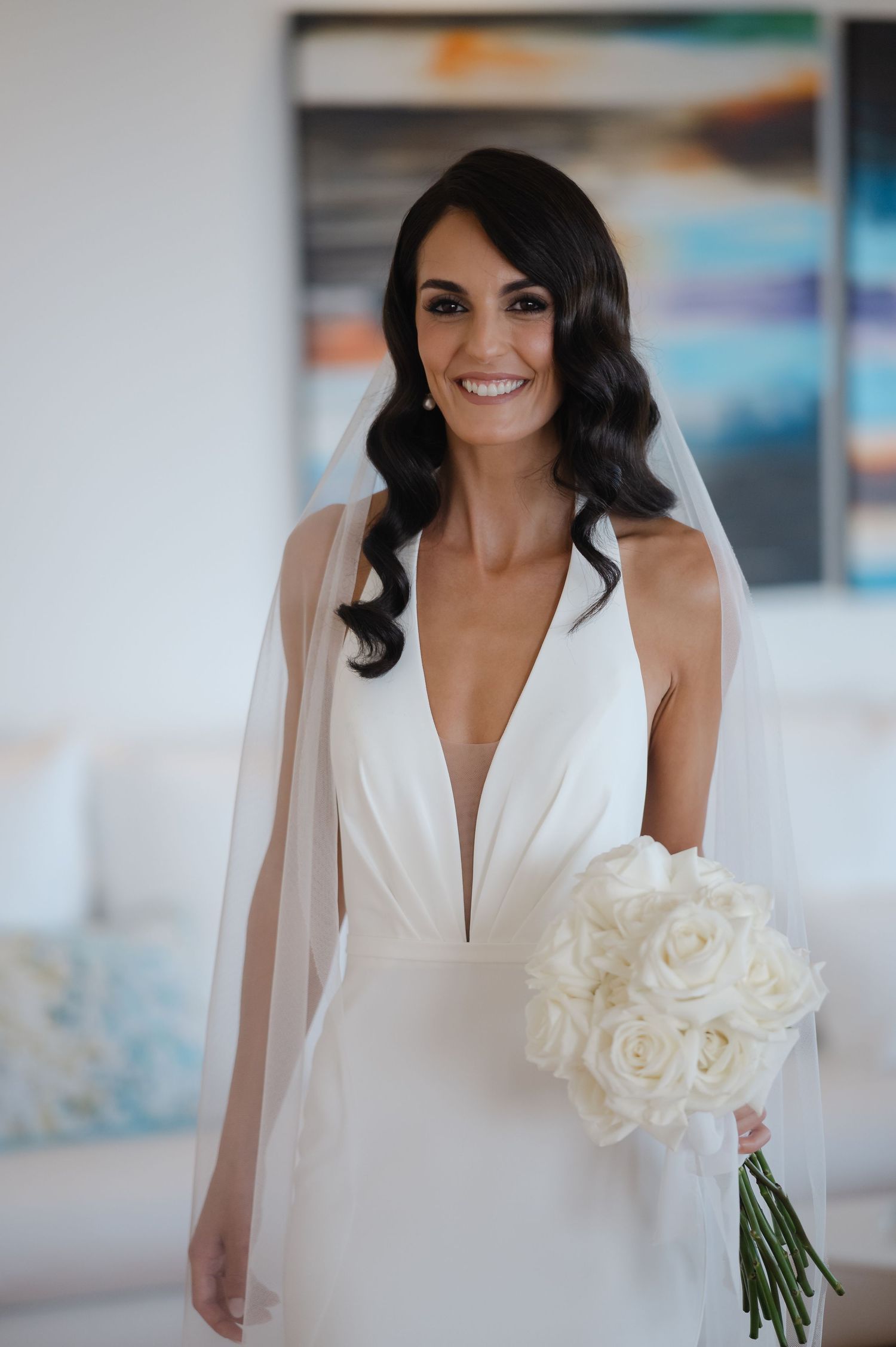 Bride in a sleek white wedding dress holding a classic white rose bouquet.