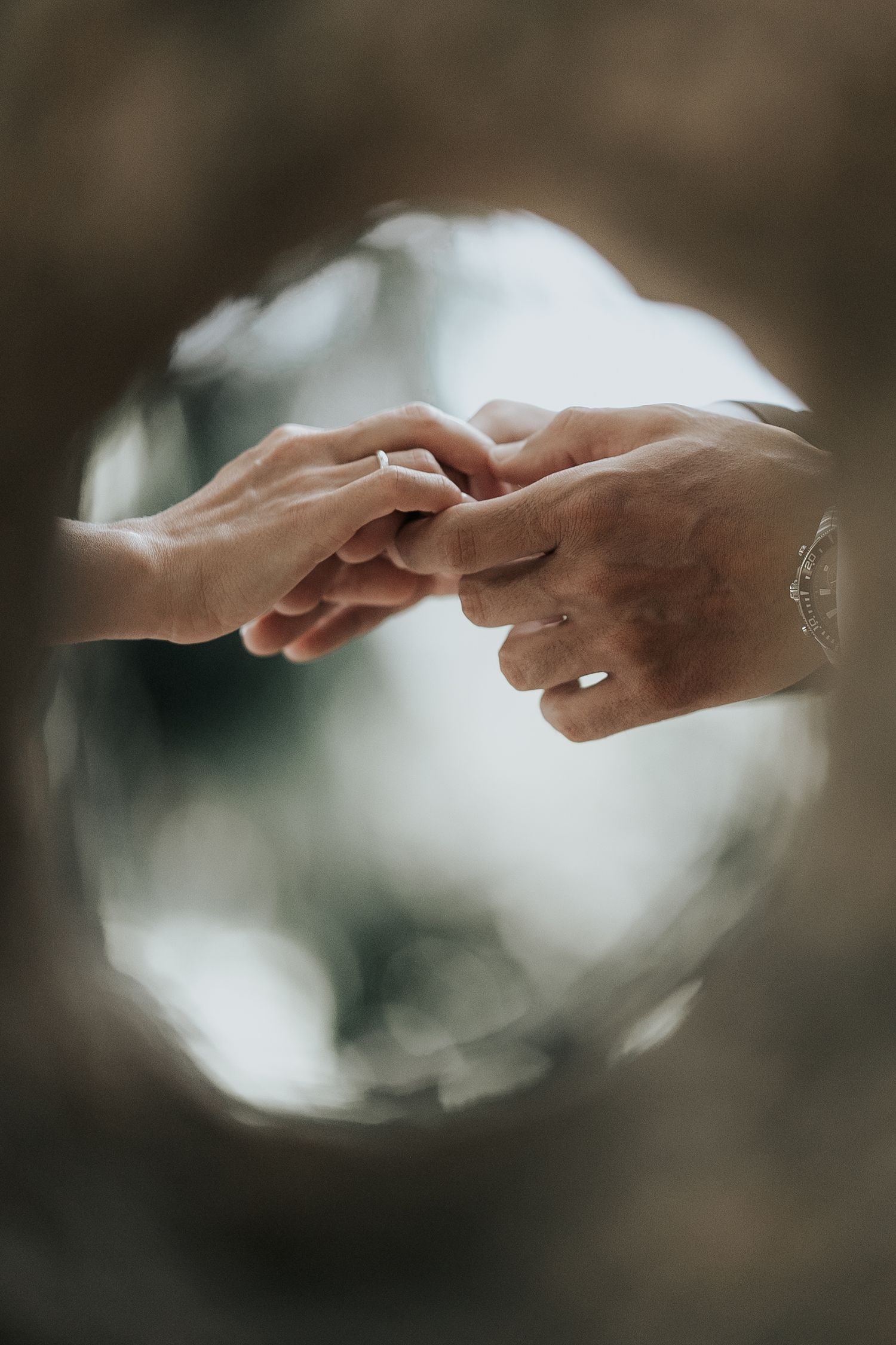Two hands reach toward each other with soft bokeh lighting effects in the background creating an ethereal atmosphere.