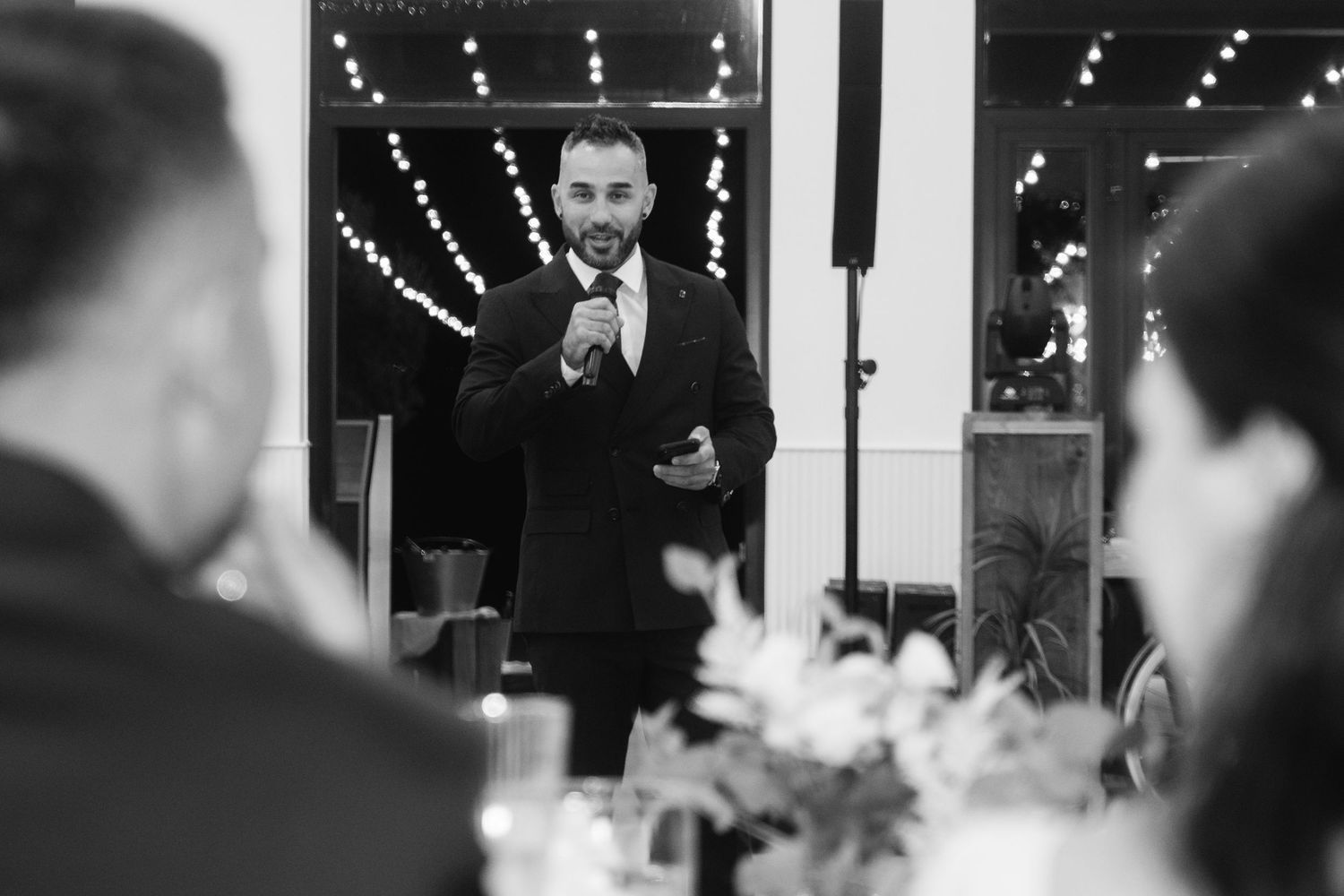 A couple shares a romantic dance moment at their wedding reception while guests look on in the background.