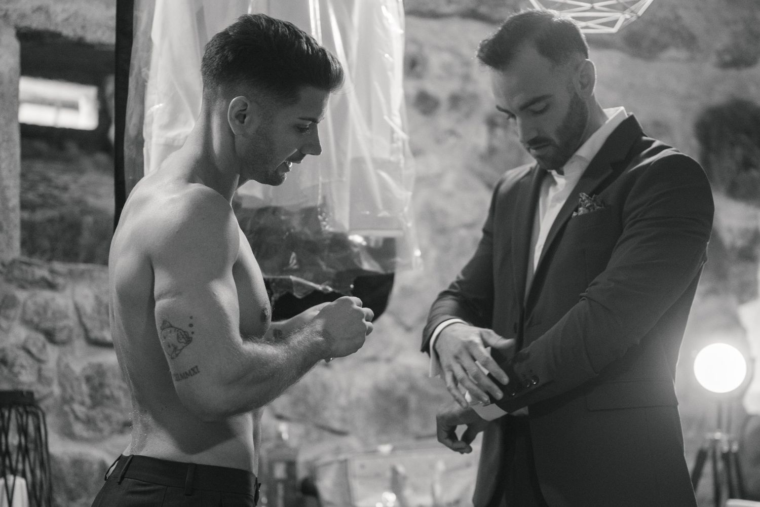 A shirtless boxer and suited trainer check time before a match in dramatic black and white lighting.