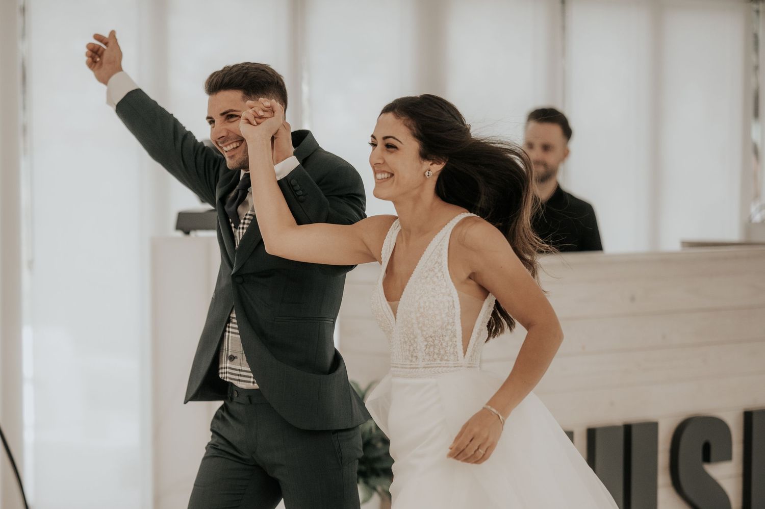 Wedding party dancing and celebrating together on a white dance floor at a reception venue.