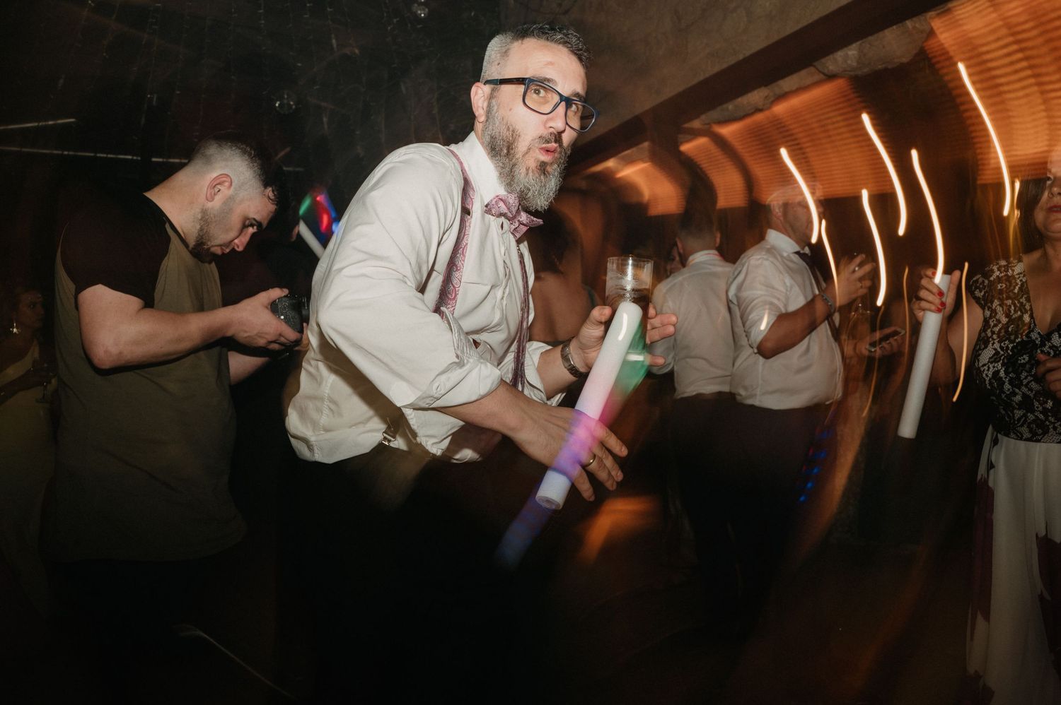 People dancing and celebrating at a lively party with warm lighting and energetic atmosphere.