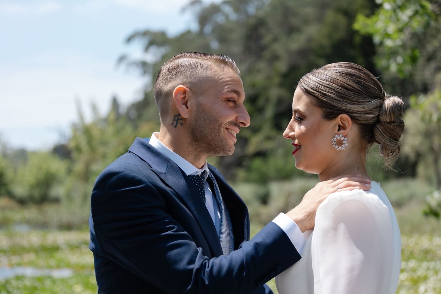 A bride and groom share romantic moments in an outdoor garden setting during their wedding photo session.