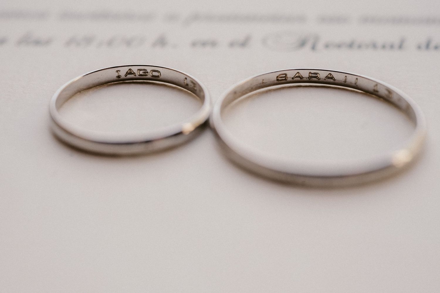 Close-up view of two simple silver wedding bands resting on a white surface.
