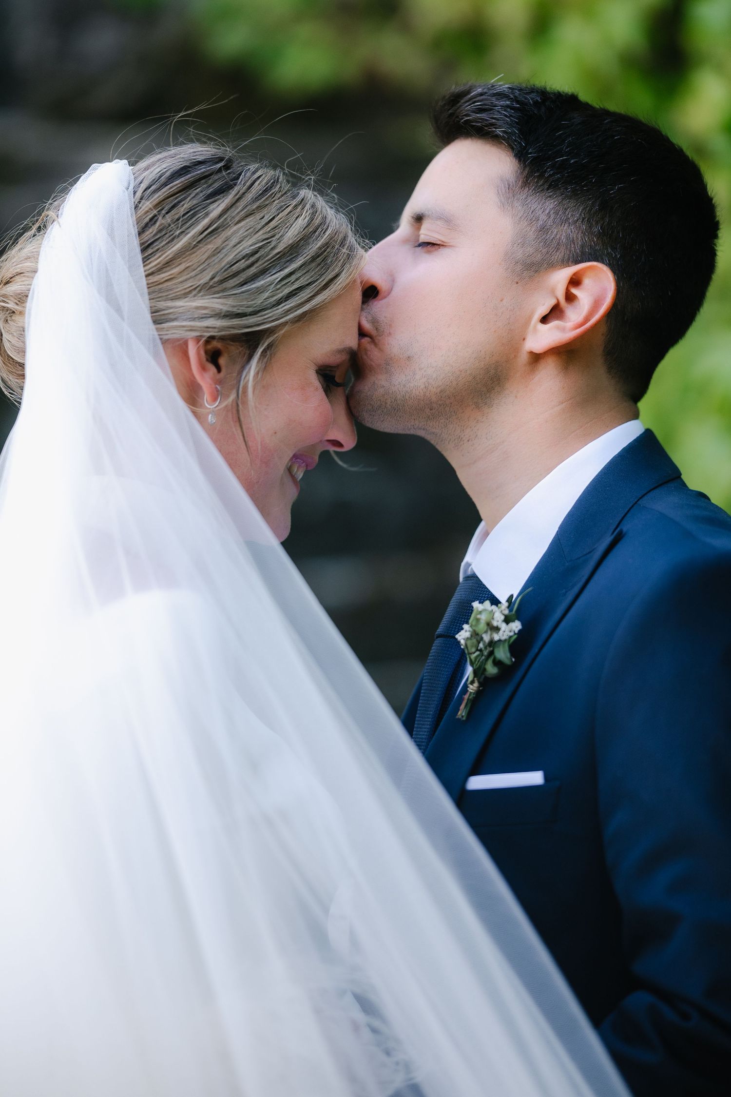 Romantic wedding portrait series showing intimate moments between newlyweds against green foliage background.