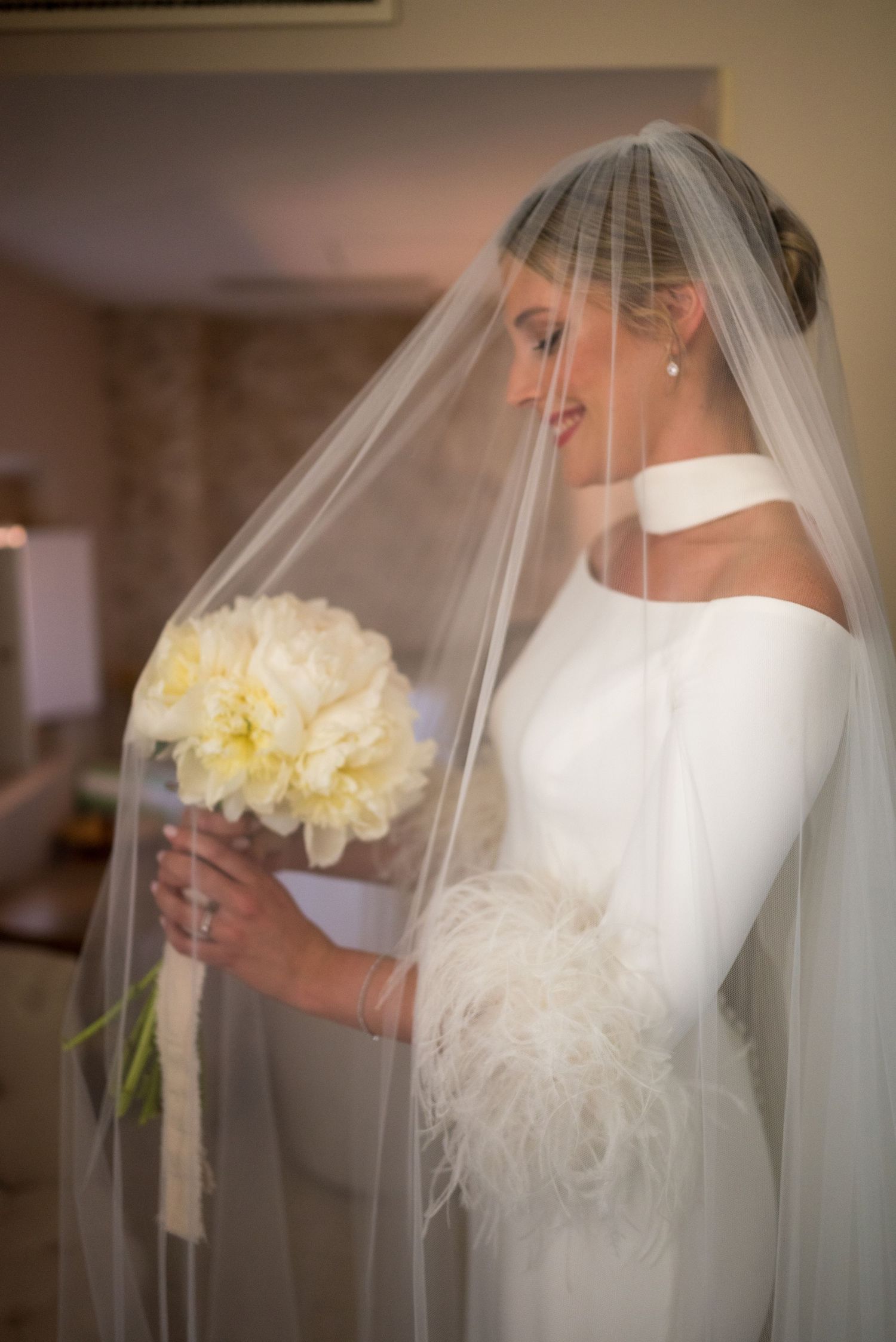 Bride in white dress holding yellow flowers with flowing veil.