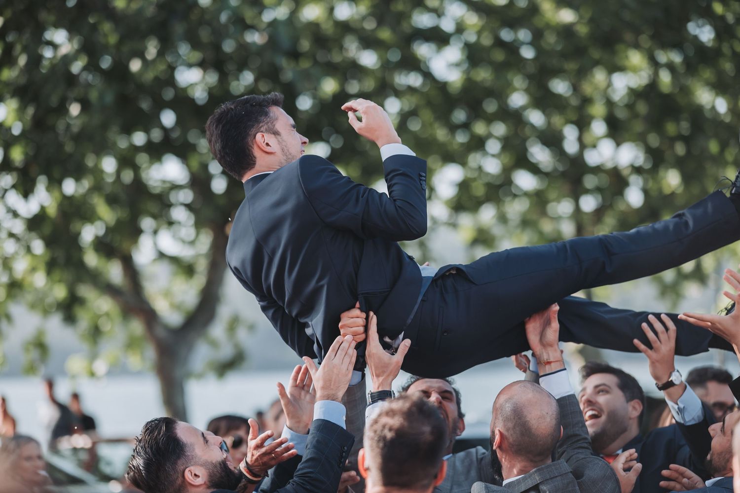 Wedding guests lift their hands in celebration during an outdoor reception.