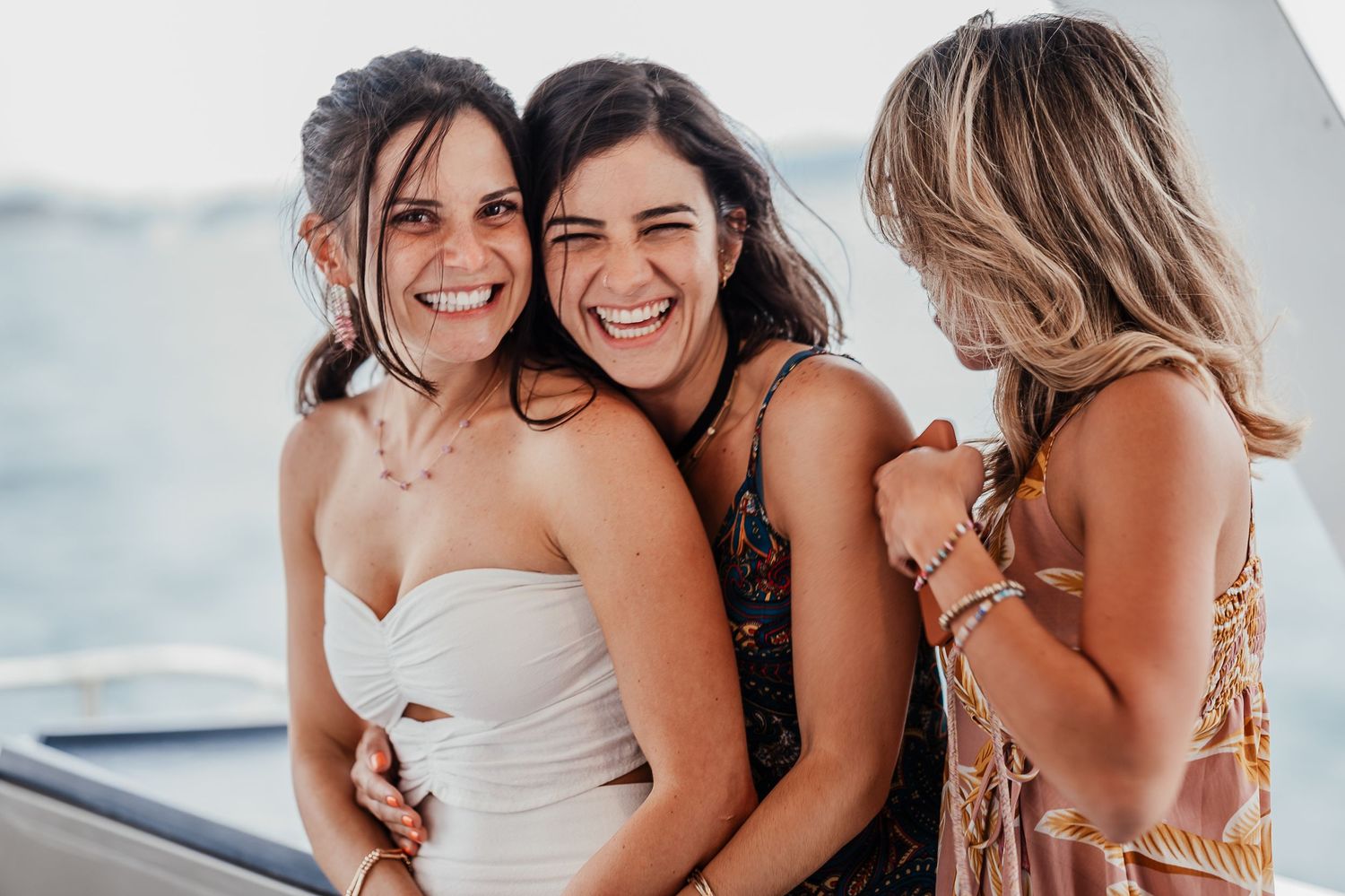 A joyful group of bridesmaids in matching pink dresses share laughter and embraces during a wedding celebration.