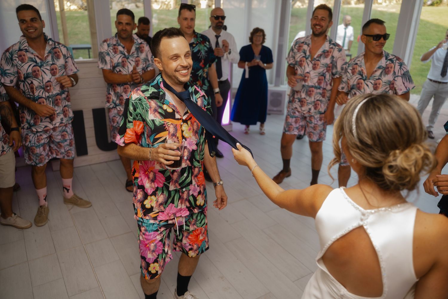 Wedding celebration showing guests in coordinated floral outfits dancing with the bride in a white dress.