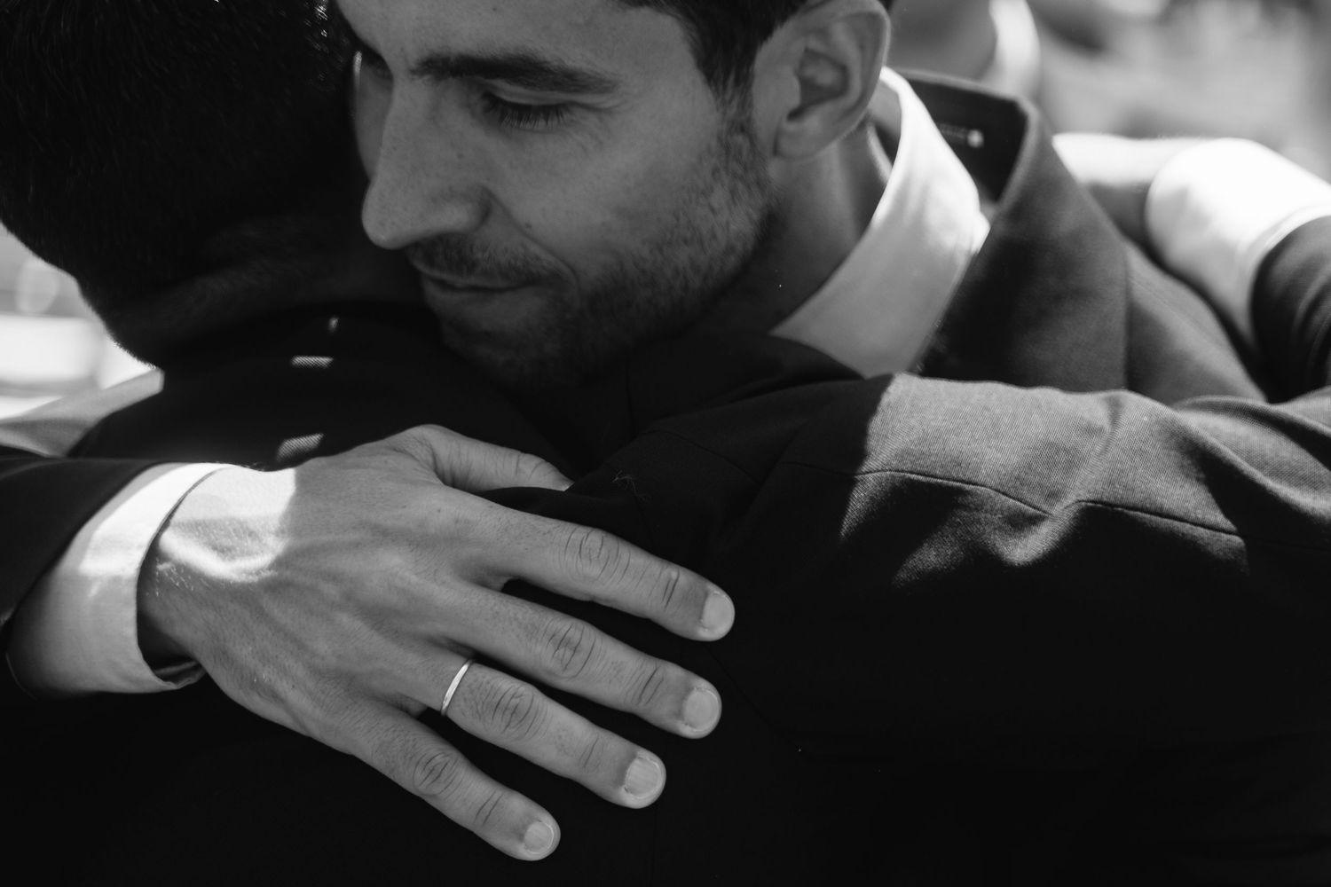 A black and white detail shot of hands holding drinks at a formal wedding event.