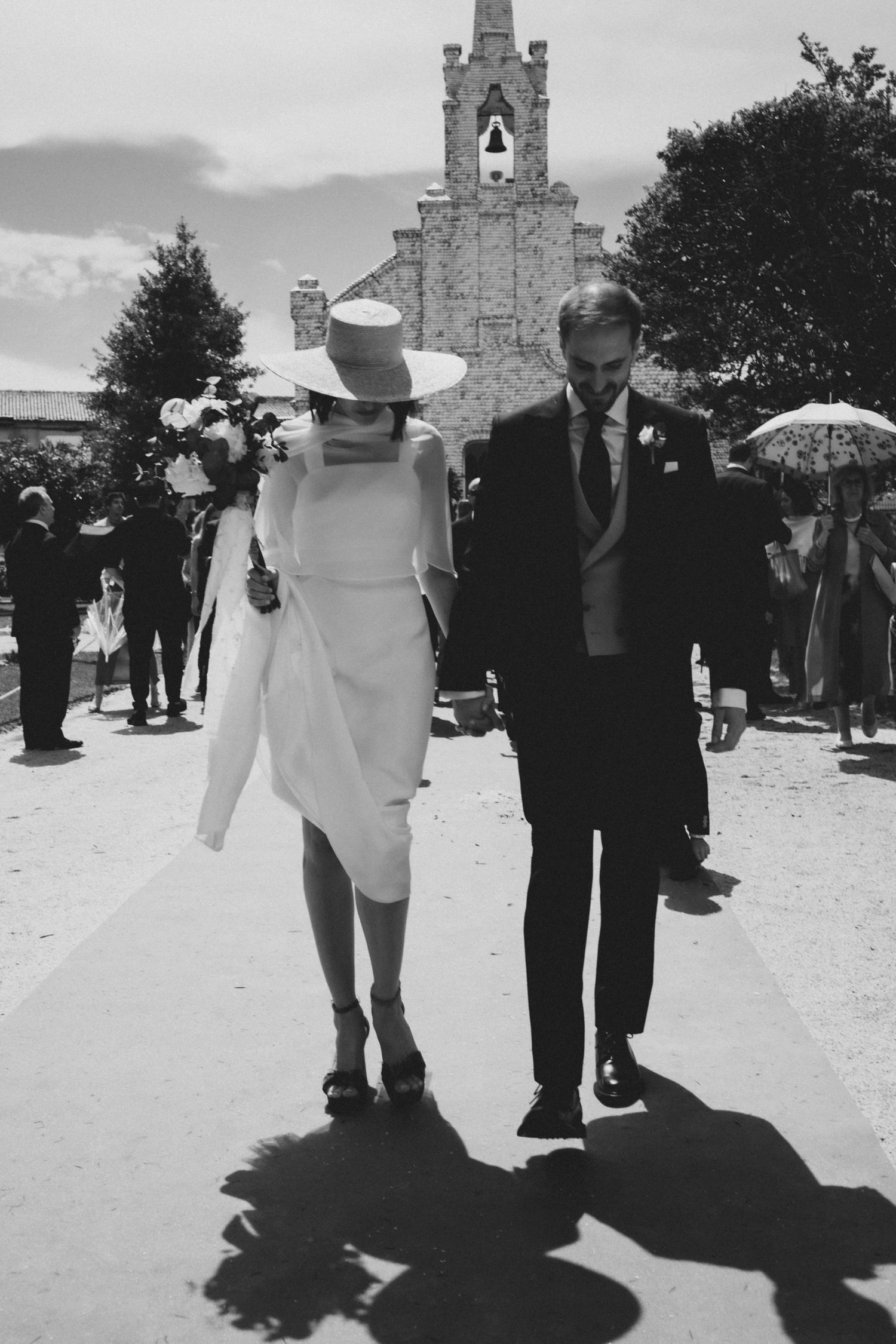 Wedding party walking along a stone path with church spires and architecture visible in the background.
