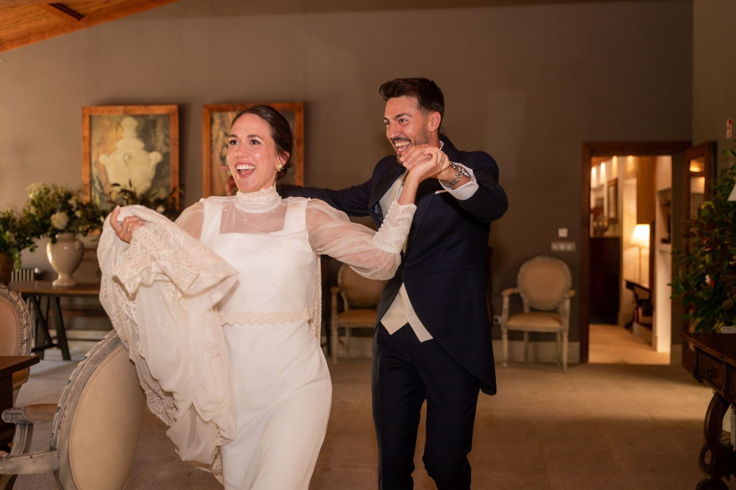 A couple dances and twirls on a wooden dance floor at their wedding reception in a warmly lit venue.