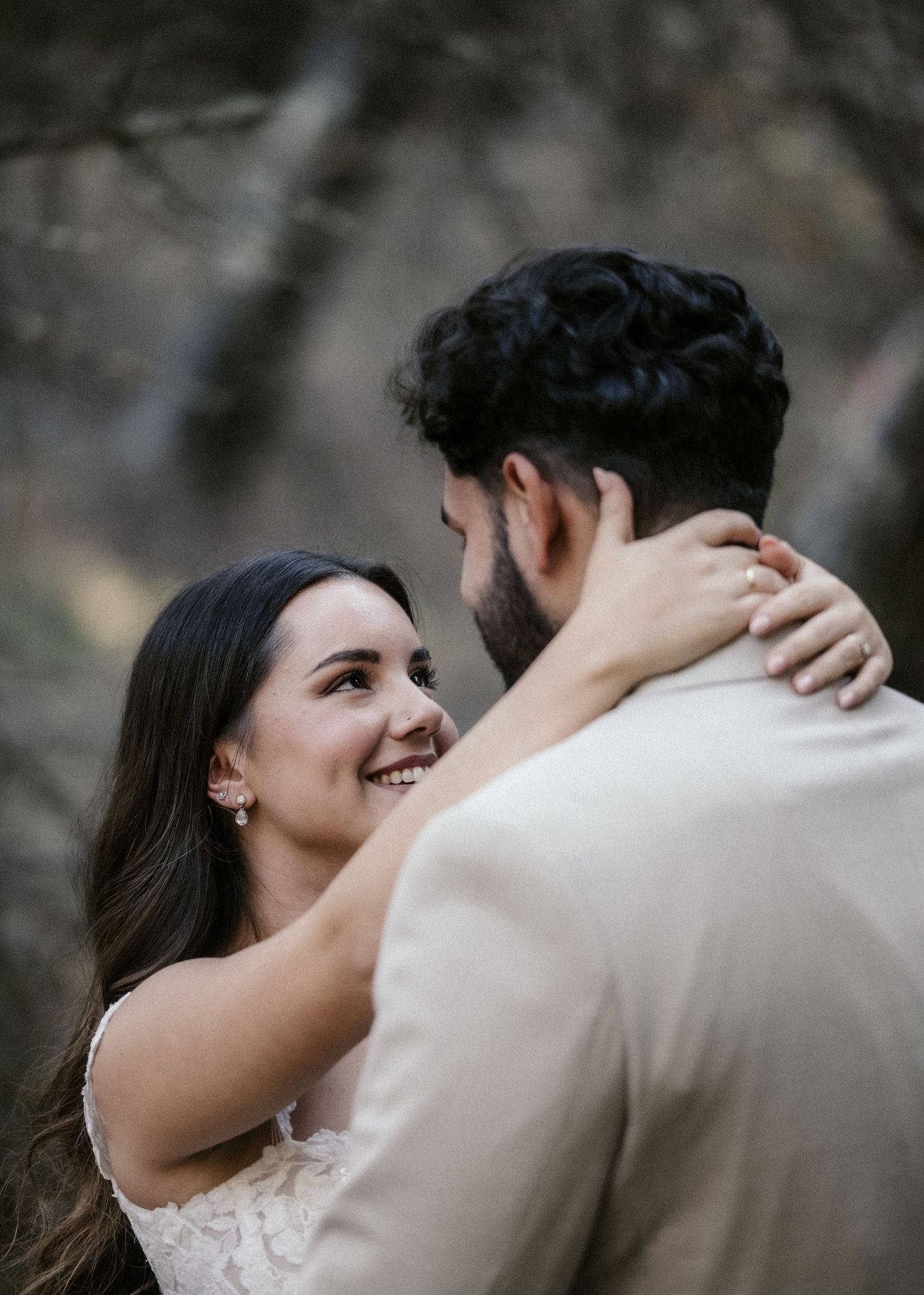 A couple embraces intimately during their wedding ceremony against a rocky backdrop.