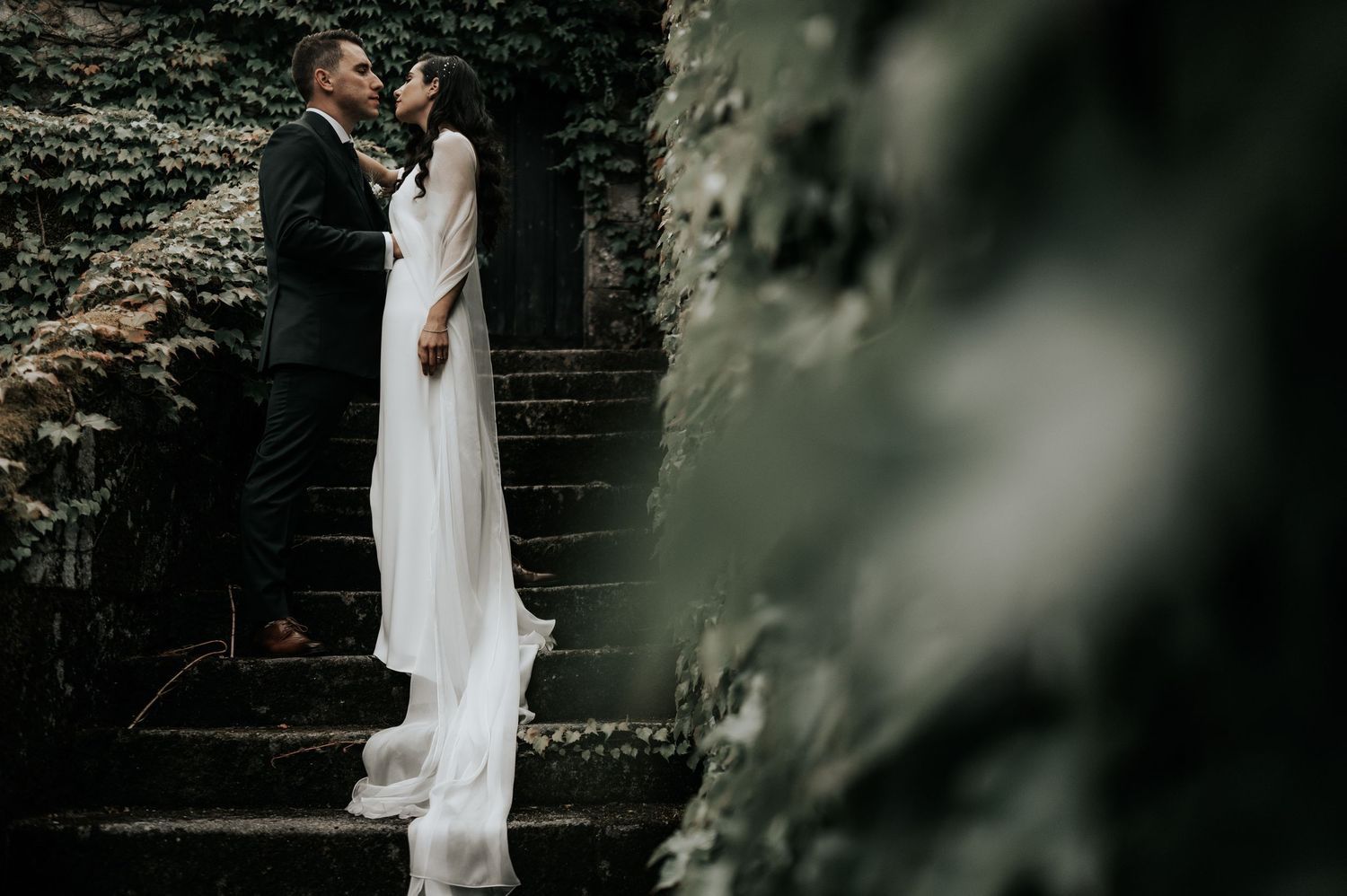 Ethereal wedding photography with soft focus and natural greenery framing the romantic scene.