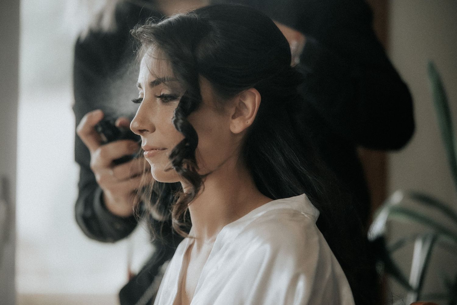 Professional makeup artist applies cosmetics to client during bridal preparation session.