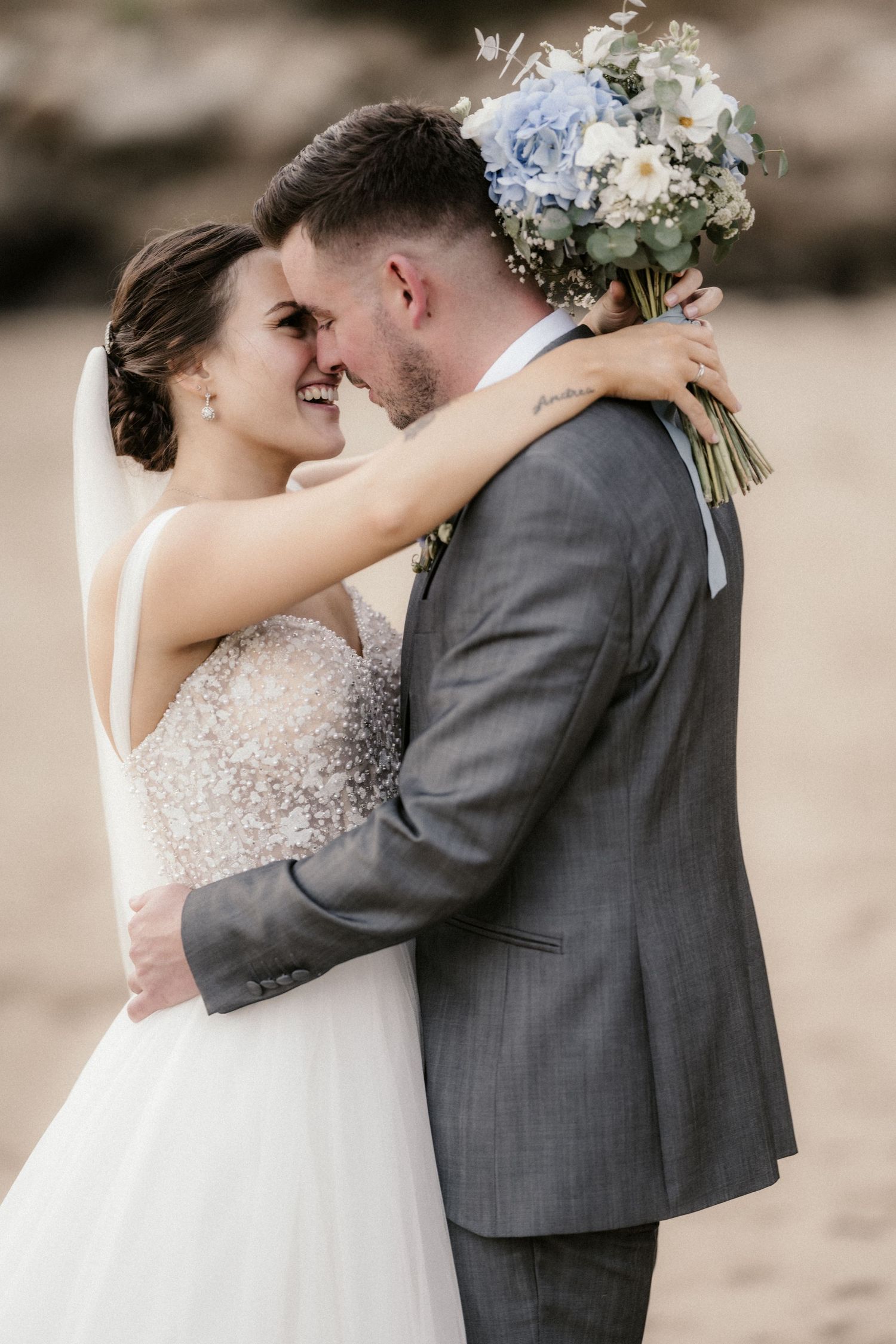 A romantic wedding couple shares an intimate kiss while embracing, with the bride in white and groom in gray suit.
