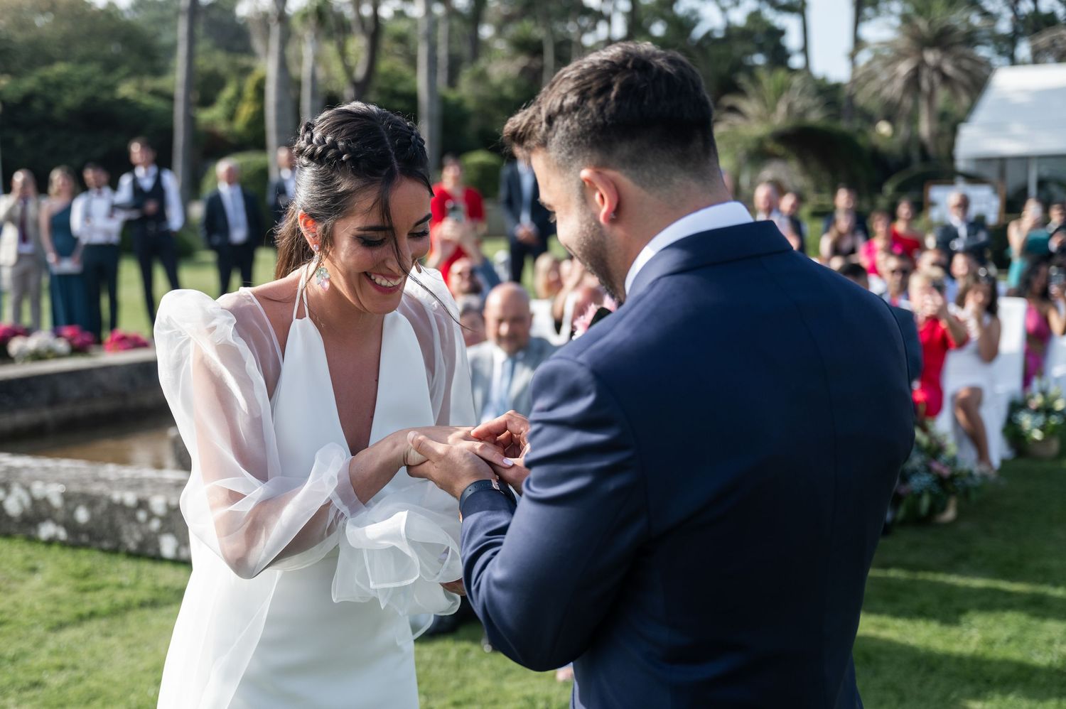 Couple dancing together outdoors during a wedding celebration with guests watching in the background.