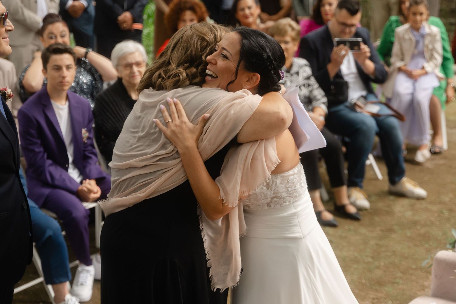A couple shares a romantic dance together at an outdoor wedding celebration with guests watching in the background.