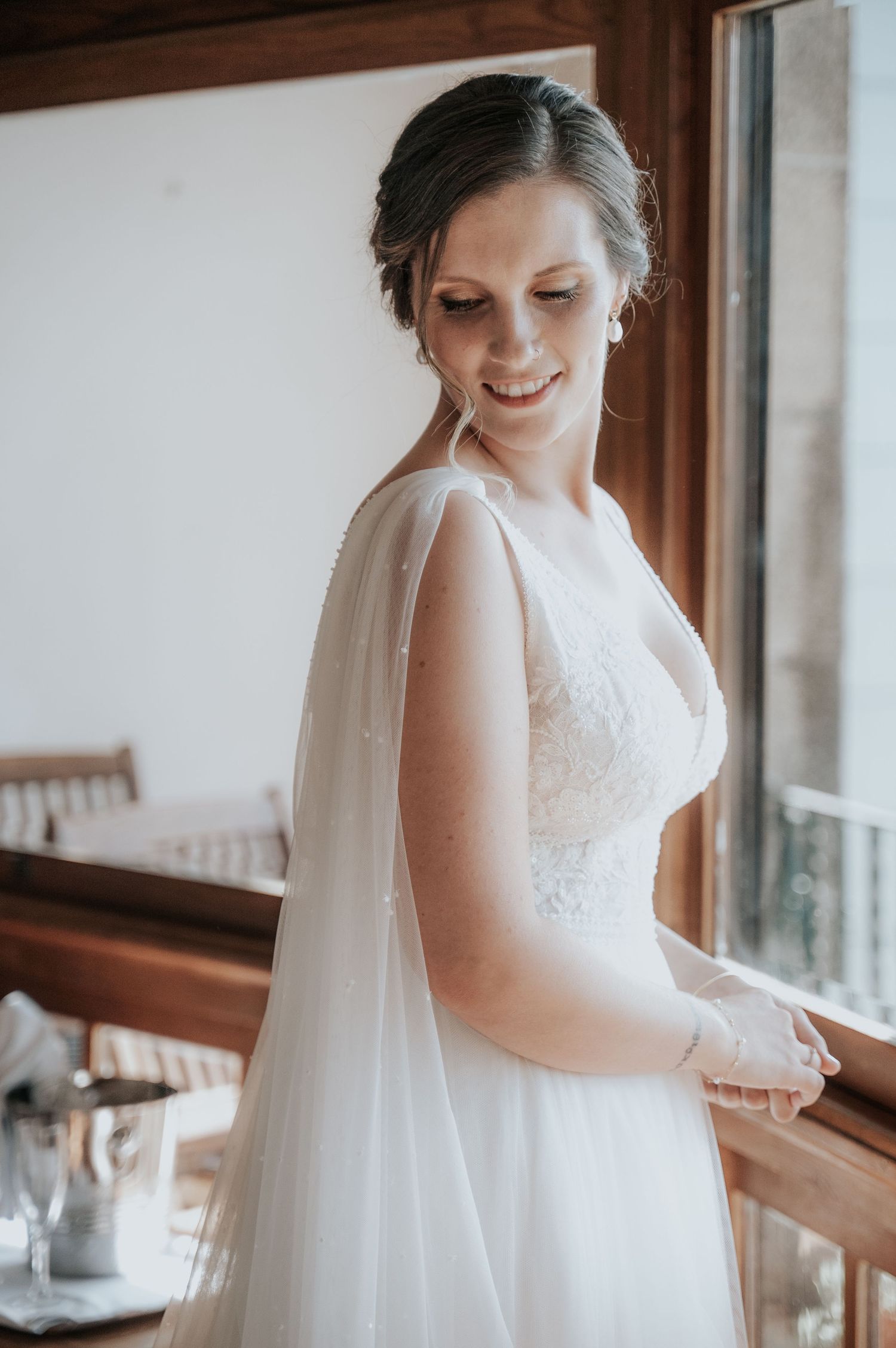 Bridal portrait session showing intricate lace details of a white wedding gown in soft window lighting.