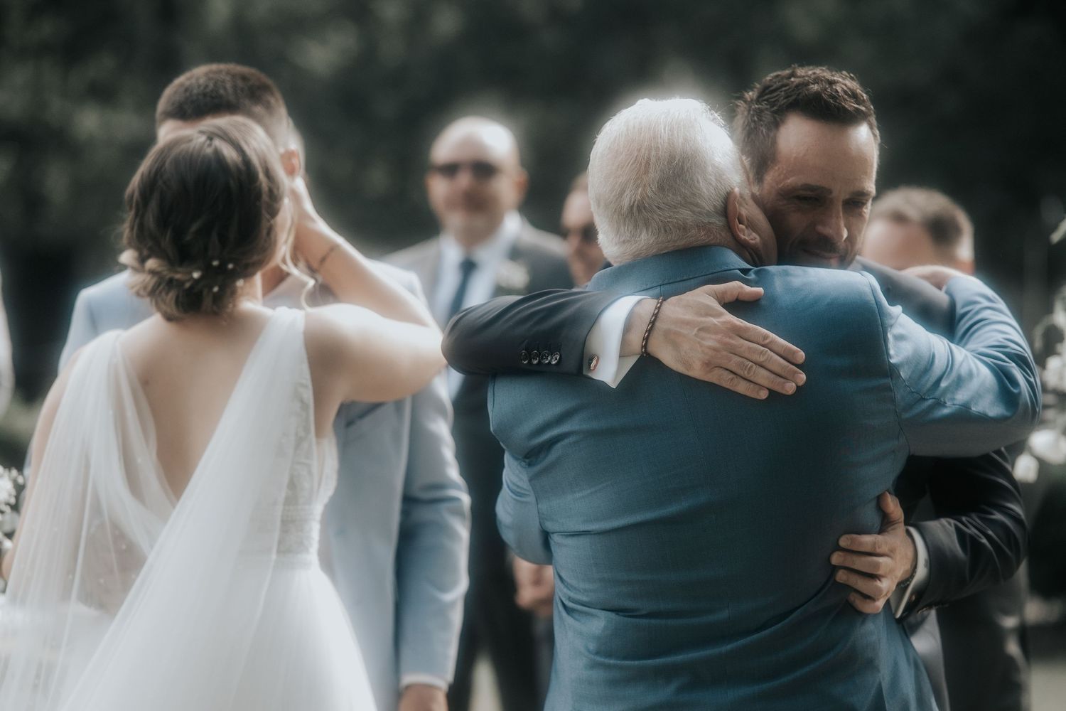 Wedding party members embrace in candid outdoor celebration moments.