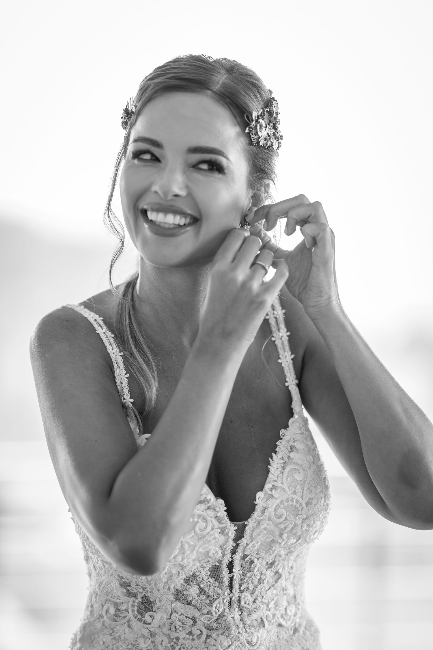 A series of black and white photos showing a bride putting on earrings while getting ready for her wedding.