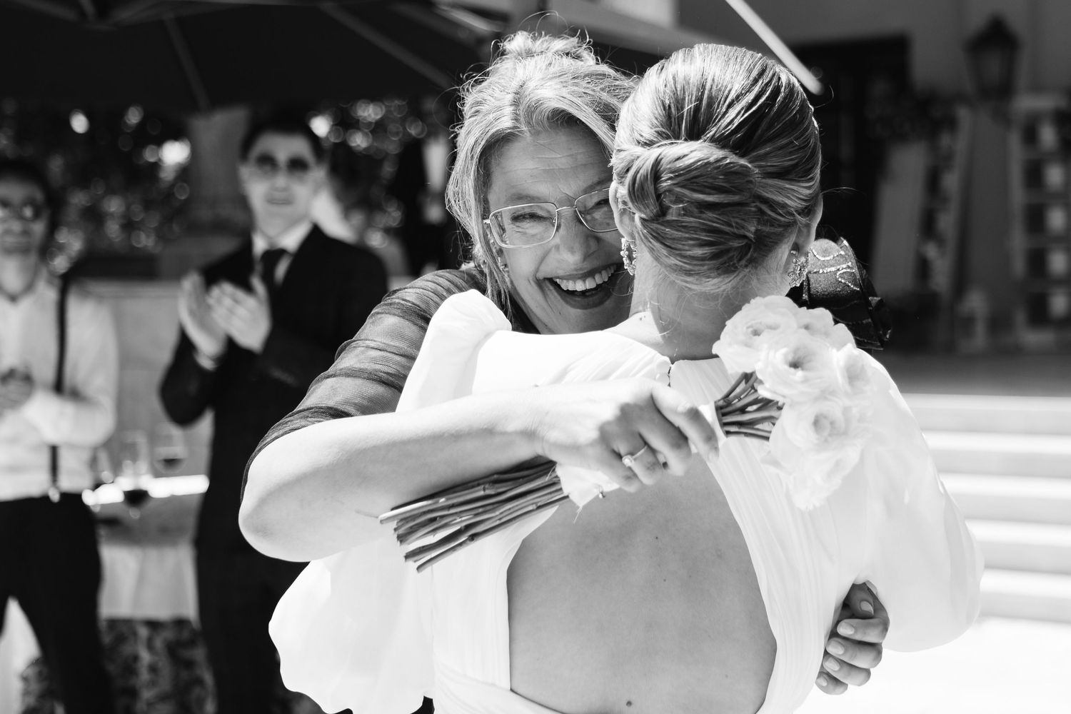 Two people in formal attire dance together during a wedding celebration on an outdoor dance floor.