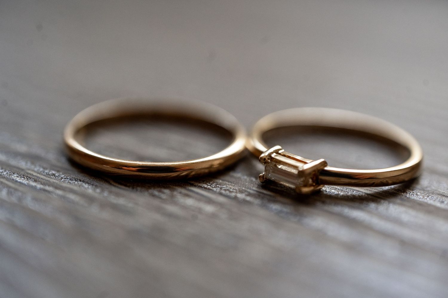 Close-up view of gold wedding rings arranged in a row on a textured gray surface.