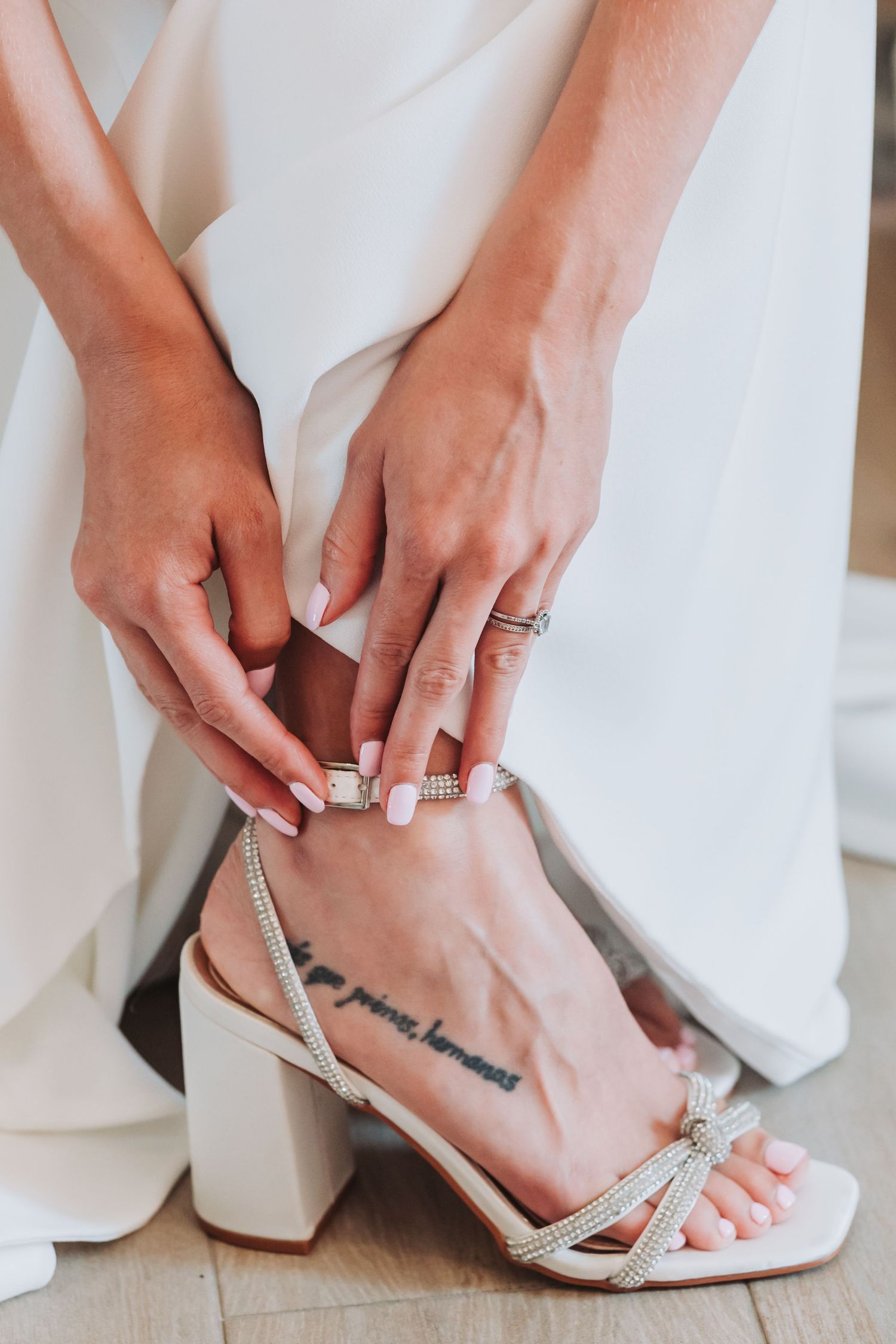 Detailed view of sparkly silver bridal sandals being secured on feet.