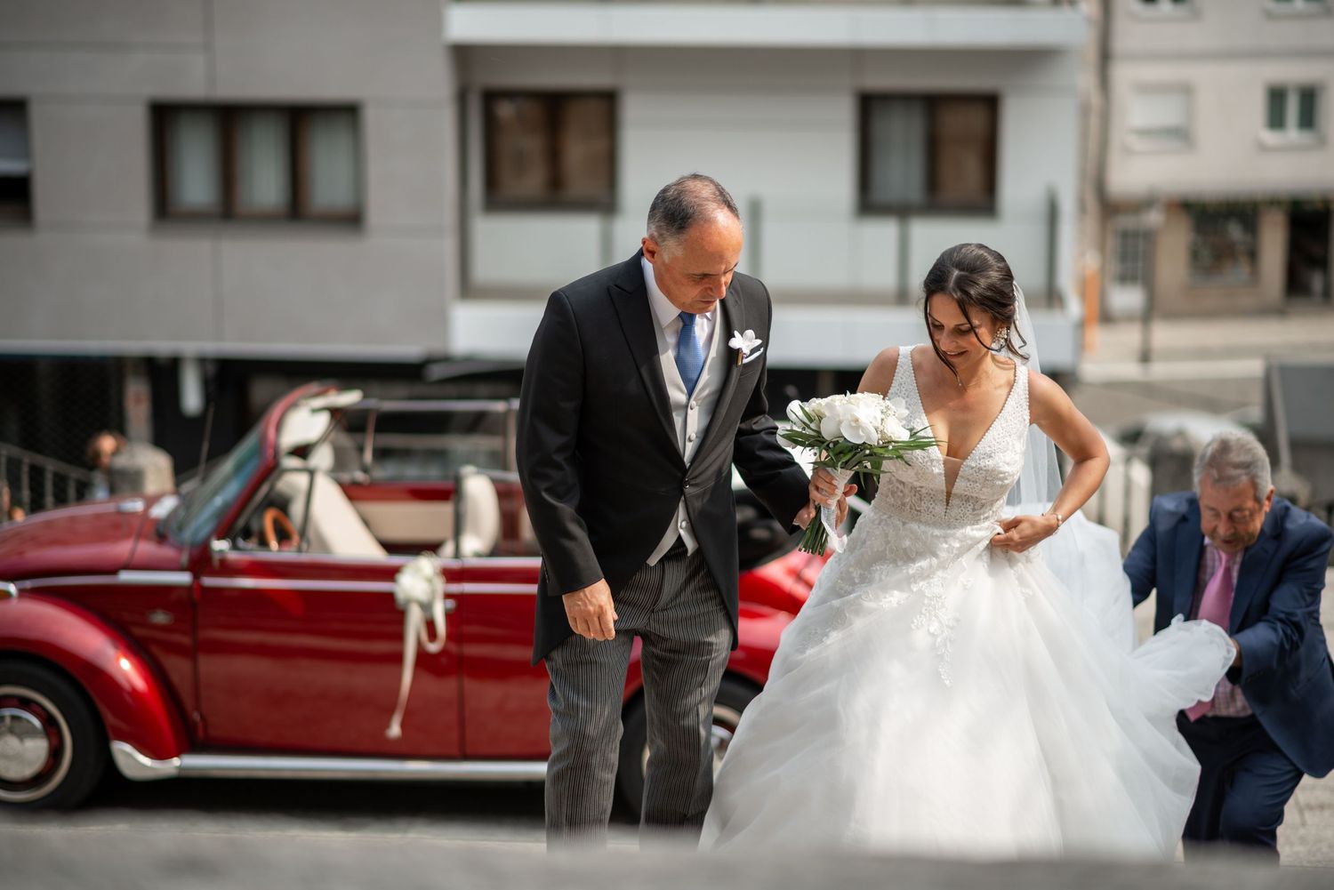 Wedding guests gather outside a church to celebrate the newlyweds with confetti and rose petals.