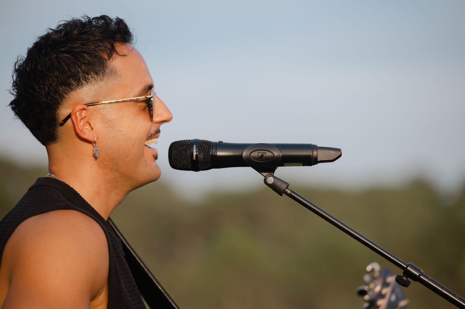 A performer sings passionately into a microphone during an outdoor concert performance.
