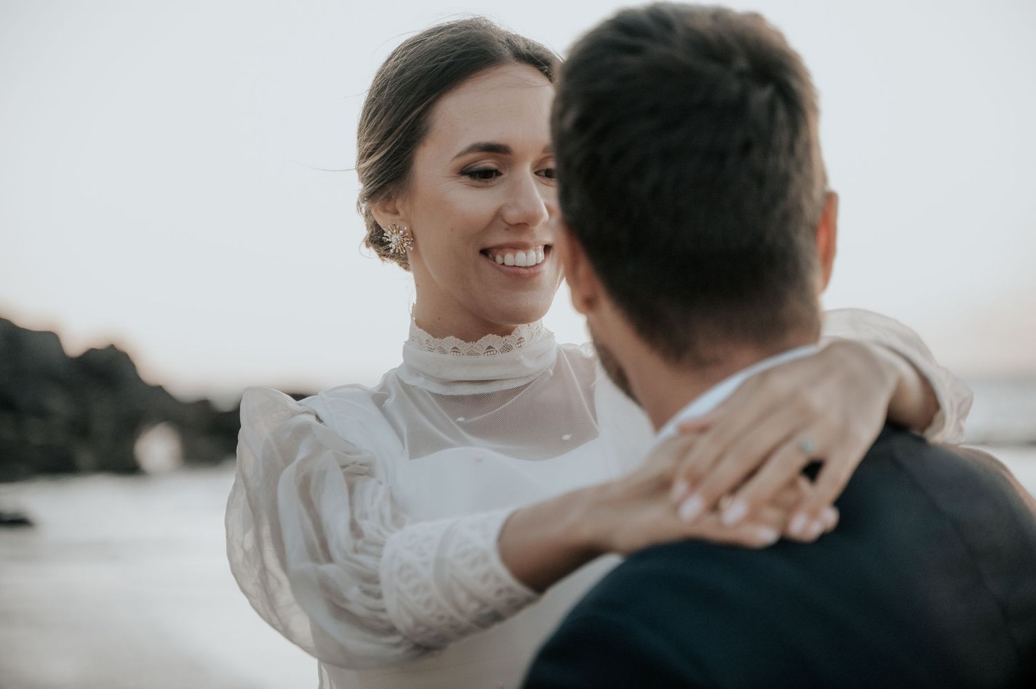 Joyful wedding couple embracing and laughing together in soft lighting.