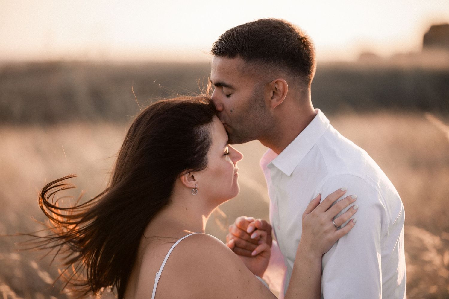 An intimate couple shares tender moments during a golden hour maternity photography session in nature.