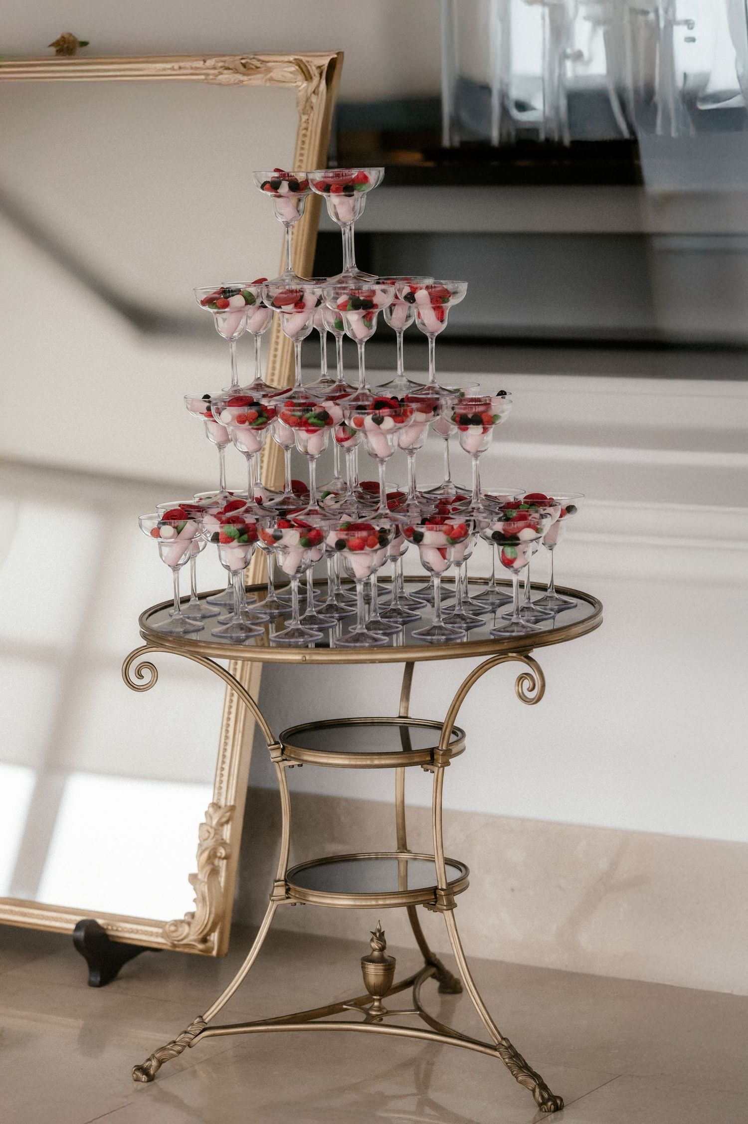 Elegant gold-trimmed round table displays multiple martini glasses arranged in circular tiers.