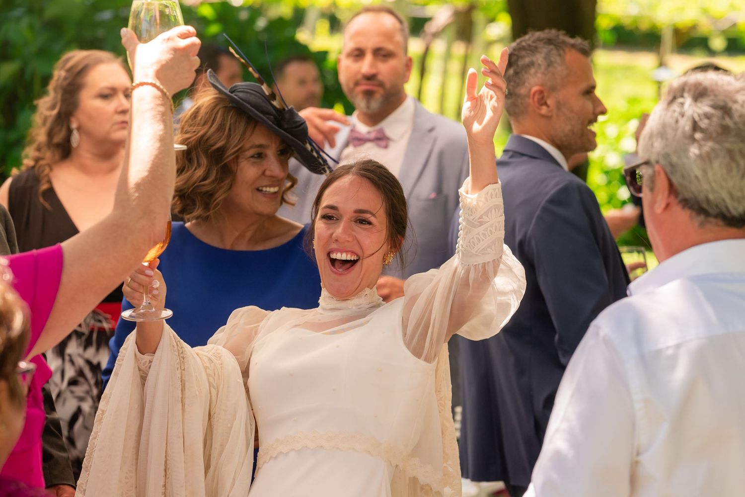 Wedding guests dancing and celebrating joyfully at an outdoor garden reception.