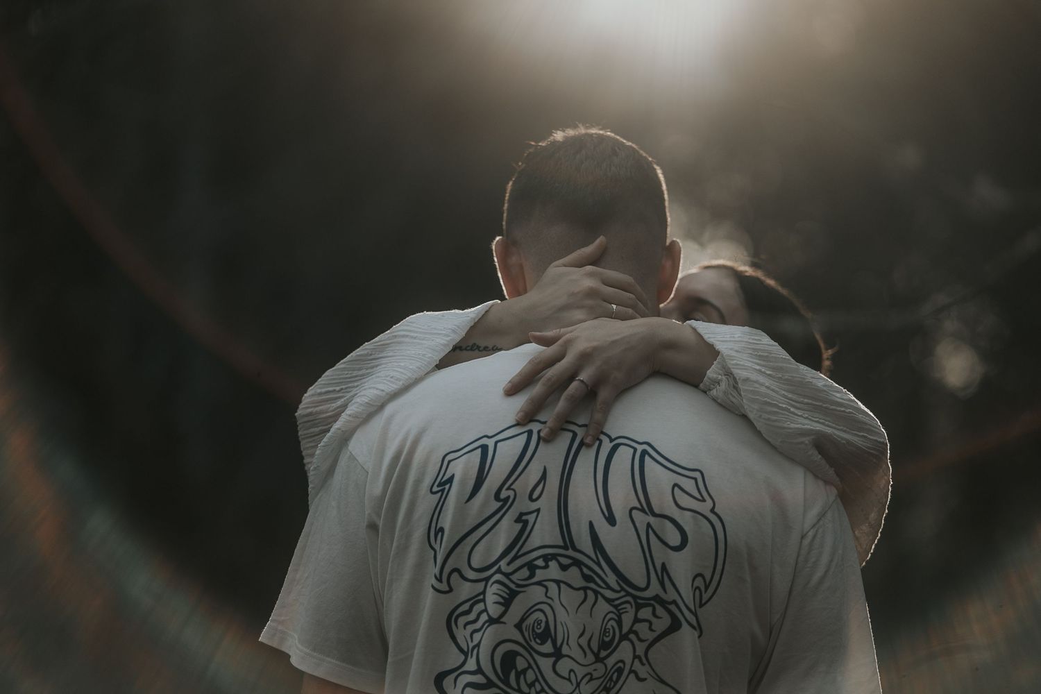 Couple walking through a misty forest path at sunset holding hands.