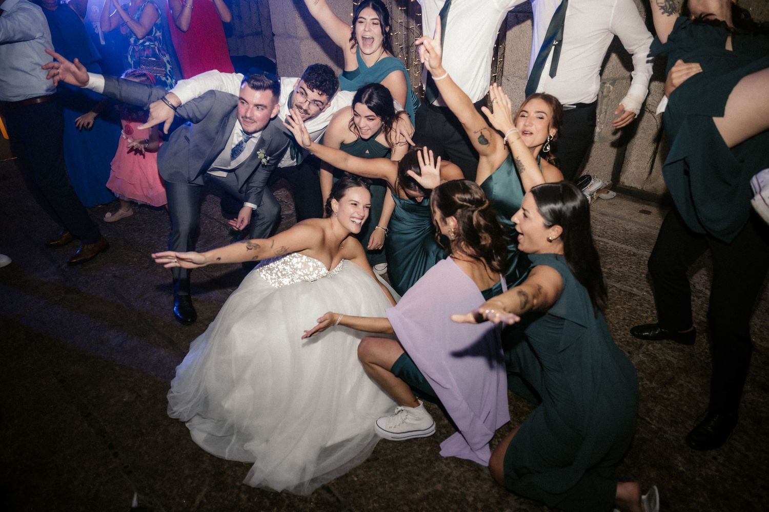 Wedding guests dancing and celebrating together on a dance floor during a festive reception party.
