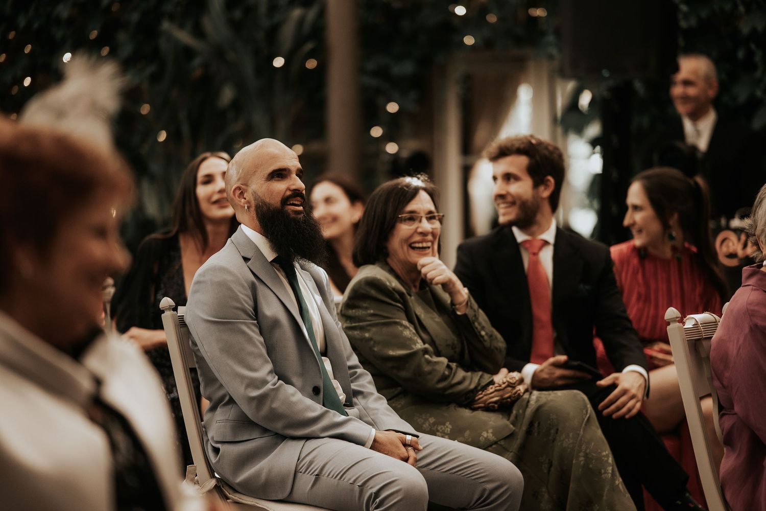 Wedding guests smile and laugh together during an intimate indoor celebration.