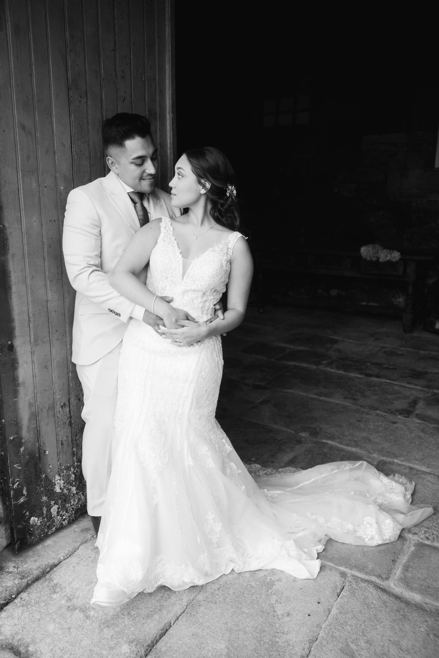 A romantic black and white wedding photo series showing a couple embracing in a rustic barn setting.